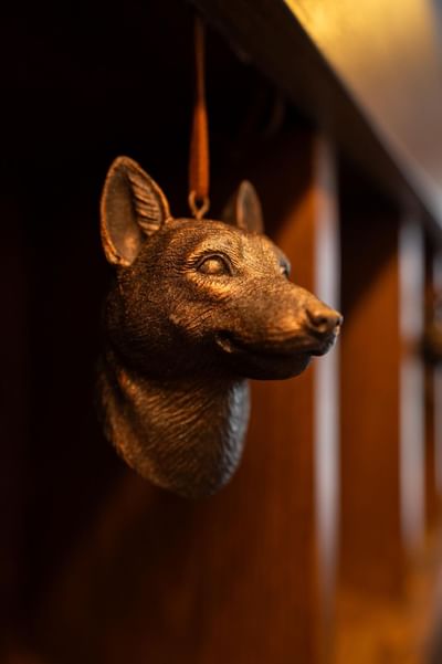 Close-up of bronze fox key fob hanging from a leather strap inside one of the wooden mail cubbies at 5Q House Quinta Camacho