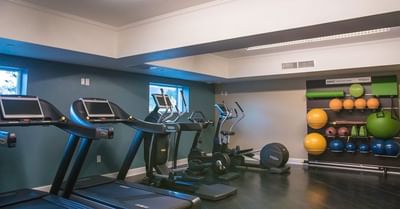 A fitness center with cardio machines and a rack of exercise balls and foam rollers at The Stanley Hotel