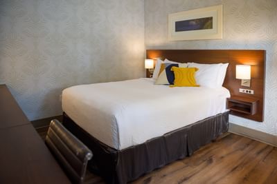 Plush king bed with a bright yellow textured pillow and lit bedside lamps in a modern guest room at Rodd Moncton