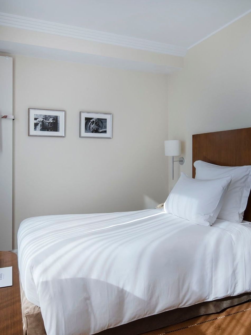 Single bed by a round side table under a wall-mounted TV in Classic Single Room at Warwick Geneva