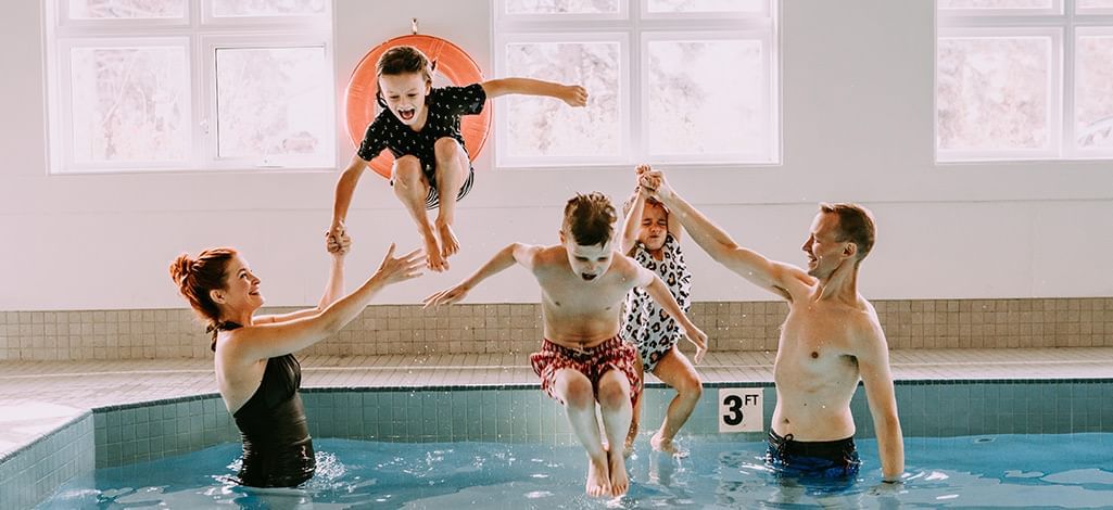 family swimming in Coast Canmore Hotel indoor pool