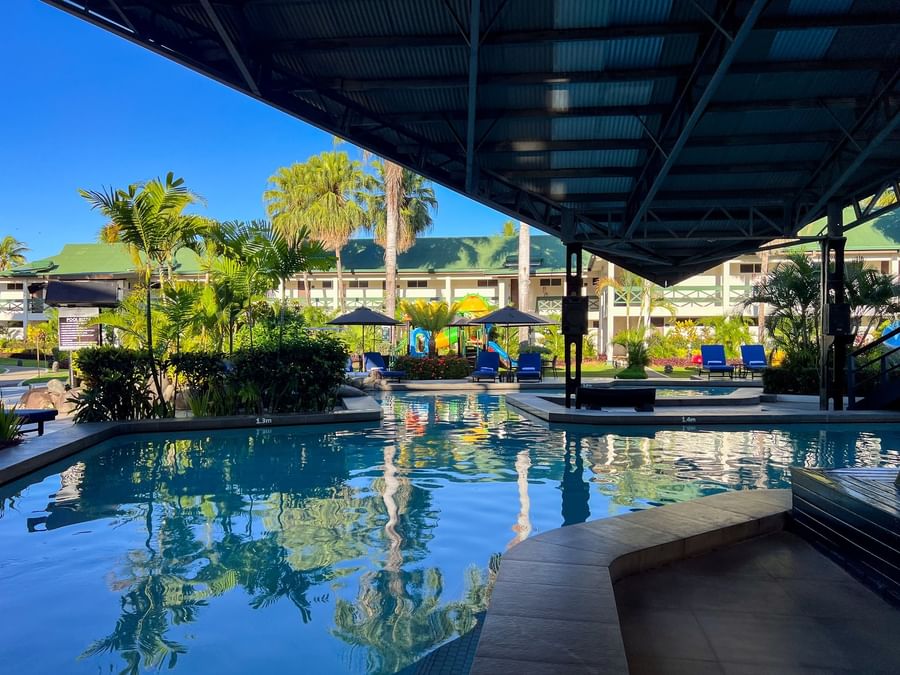 Winding swimming pool with palm tree reflections under a large metal shade structure at TokaToka Resort Nadi Fiji