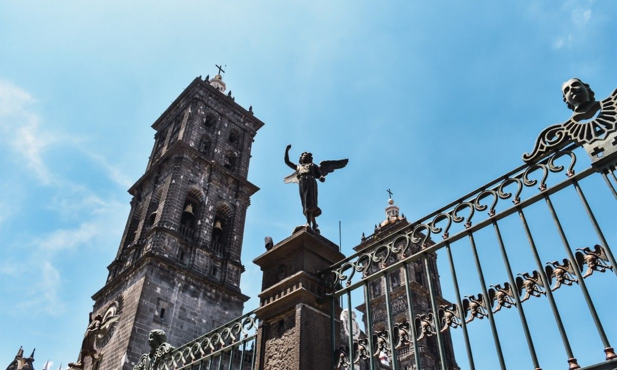 Angel statue by a tall tower under a blue sky surrounding the metal gate at Camino Real Pedregal Mexico