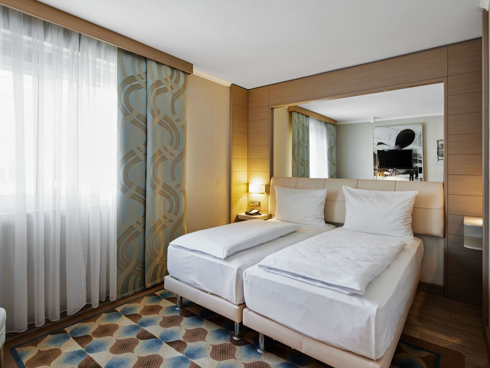 Superior-Zimmer mit zwei Einzelbetten, einem großen Spiegel und hohem Fenster im Titanic Comfort Mitte