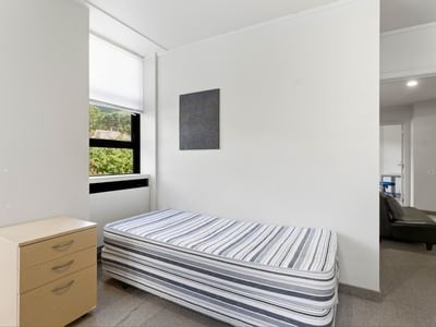Bedroom with single bed and wooden dresser at UniLodge Stafford House.