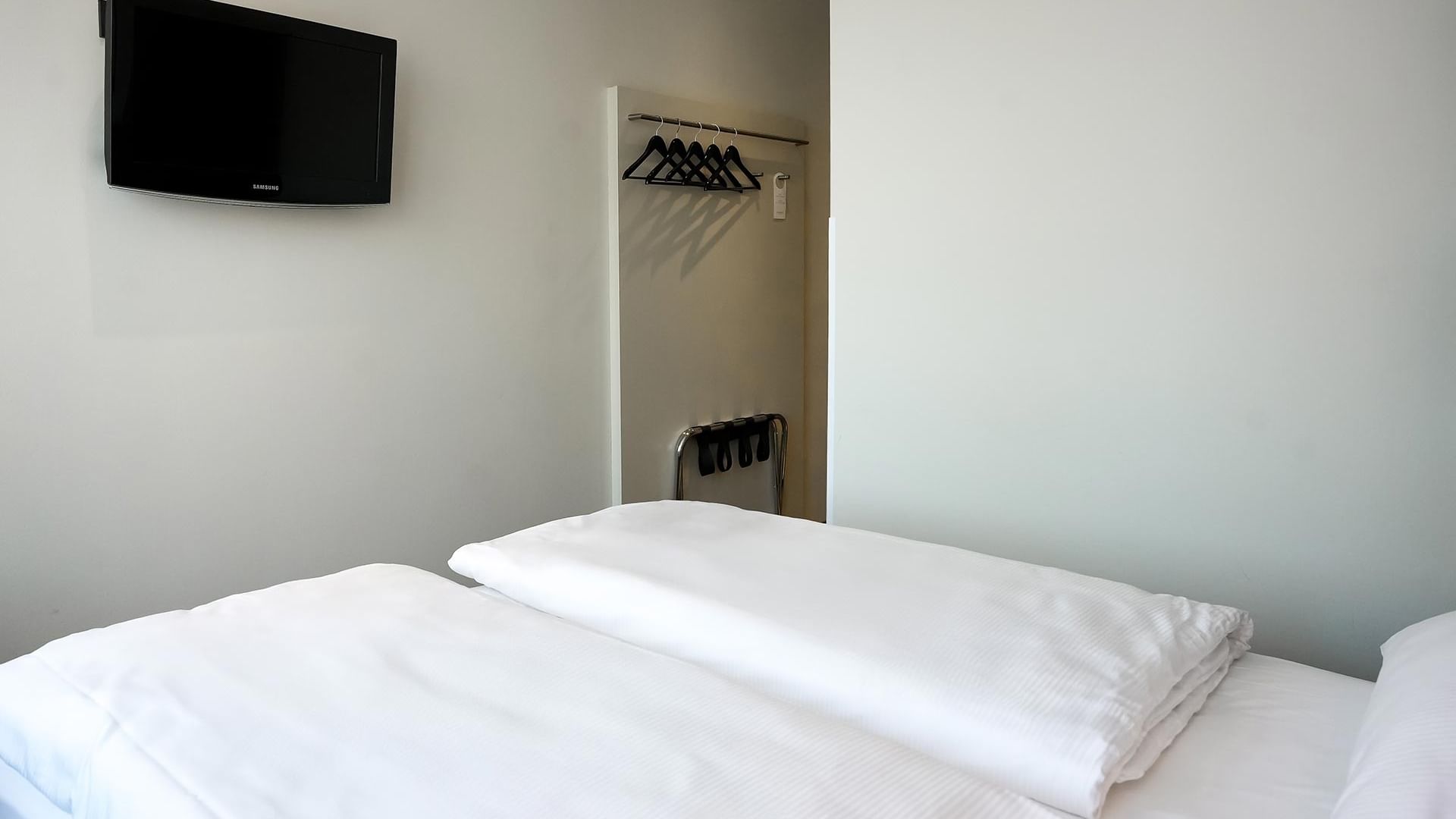 Zimmer mit Doppelbett, Fernseher und Kleiderschrank im Sylter Hof Berlin.