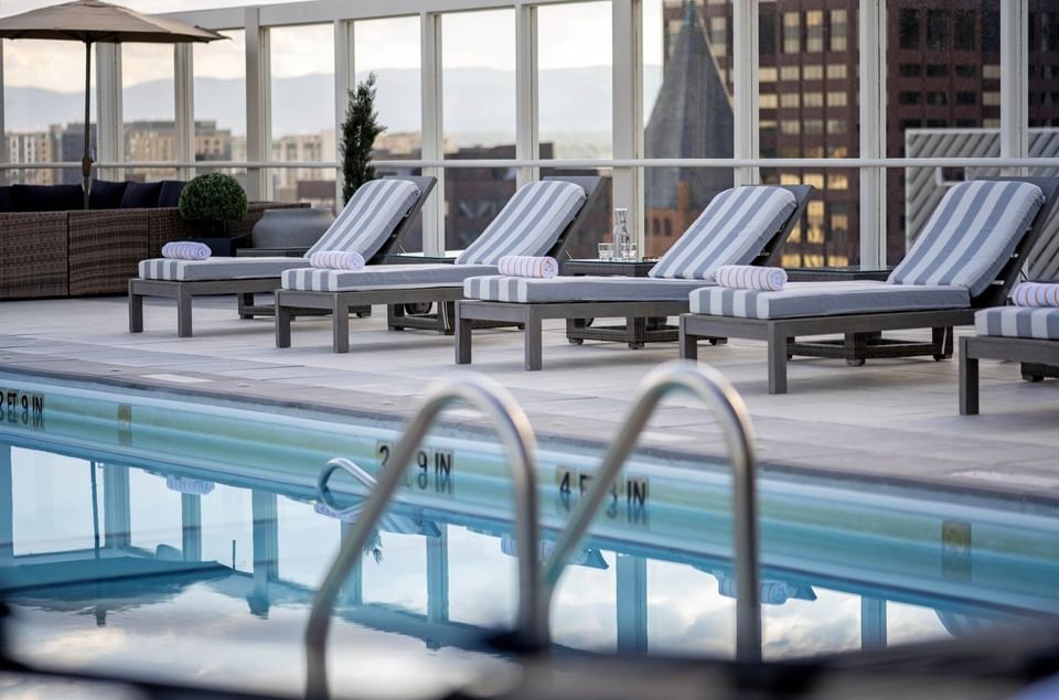 Striped loungers with towels by a glass railing near a Rooftop Pool 4 at Warwick Denver
