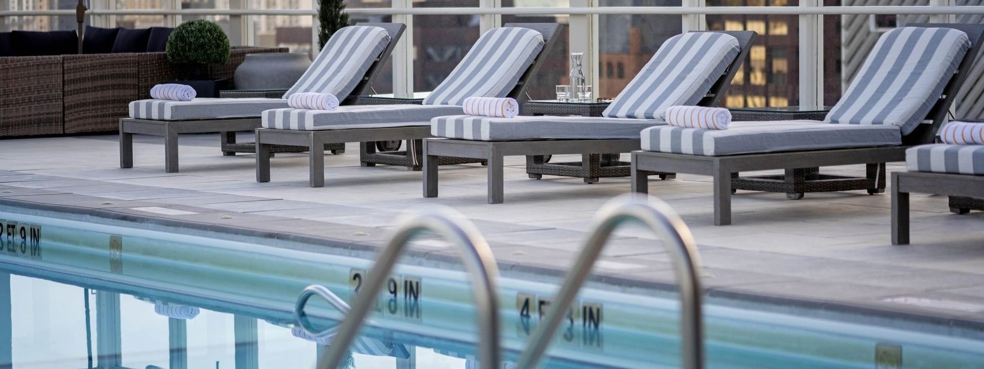 Striped loungers with towels by a glass railing near a Rooftop Pool 4 at Warwick Denver