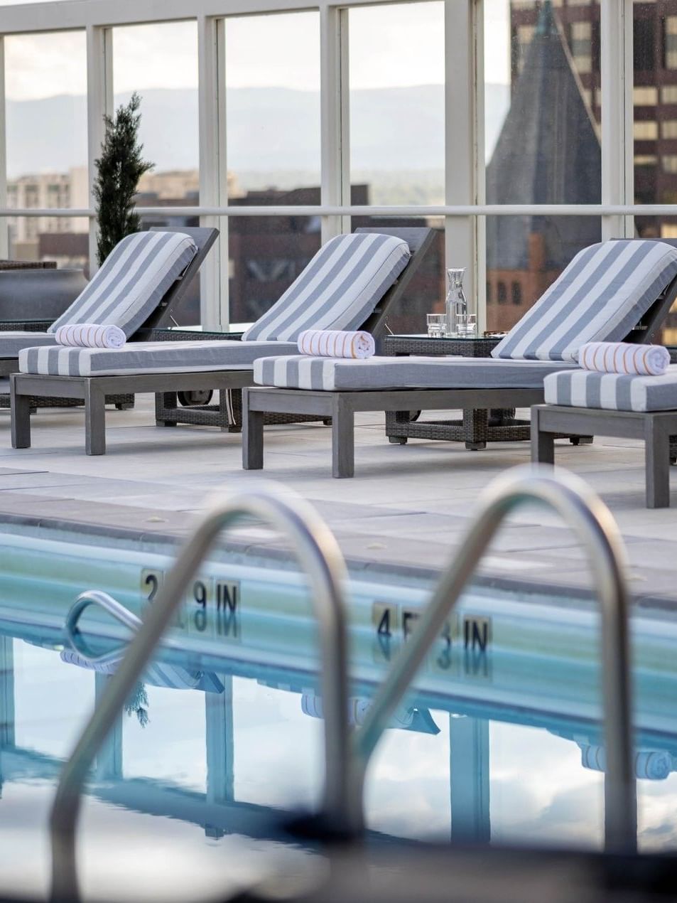Striped loungers with towels by a glass railing near a Rooftop Pool 4 at Warwick Denver