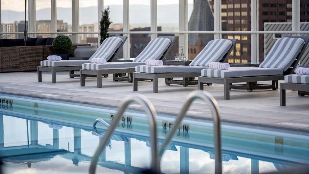 Striped loungers with towels by a glass railing near a Rooftop Pool 4 at Warwick Denver