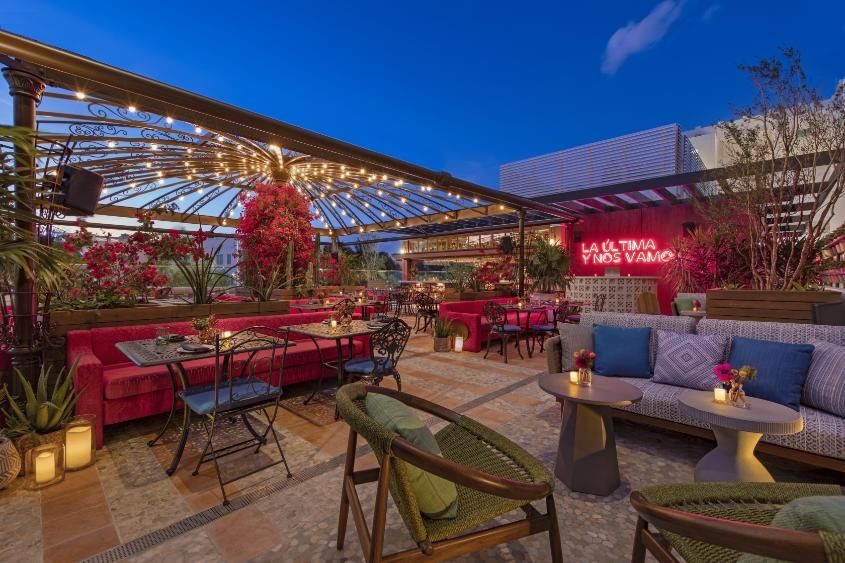 A stylish outdoor bar with seating, string lights, and plants