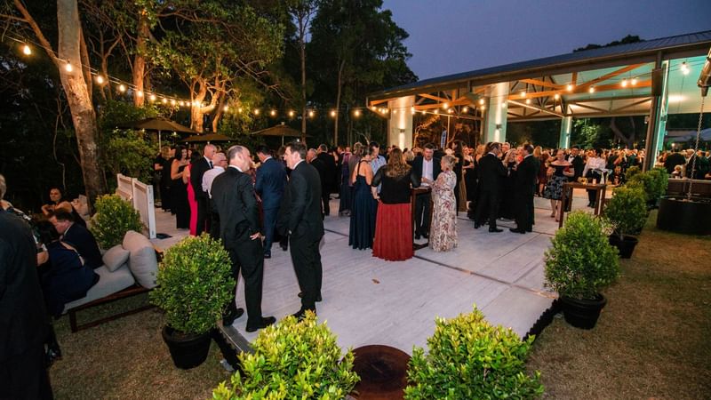 Guests mingling in the Arrivals lounge, surrounded by greenery and string lights at Novotel Sunshine Coast Resort