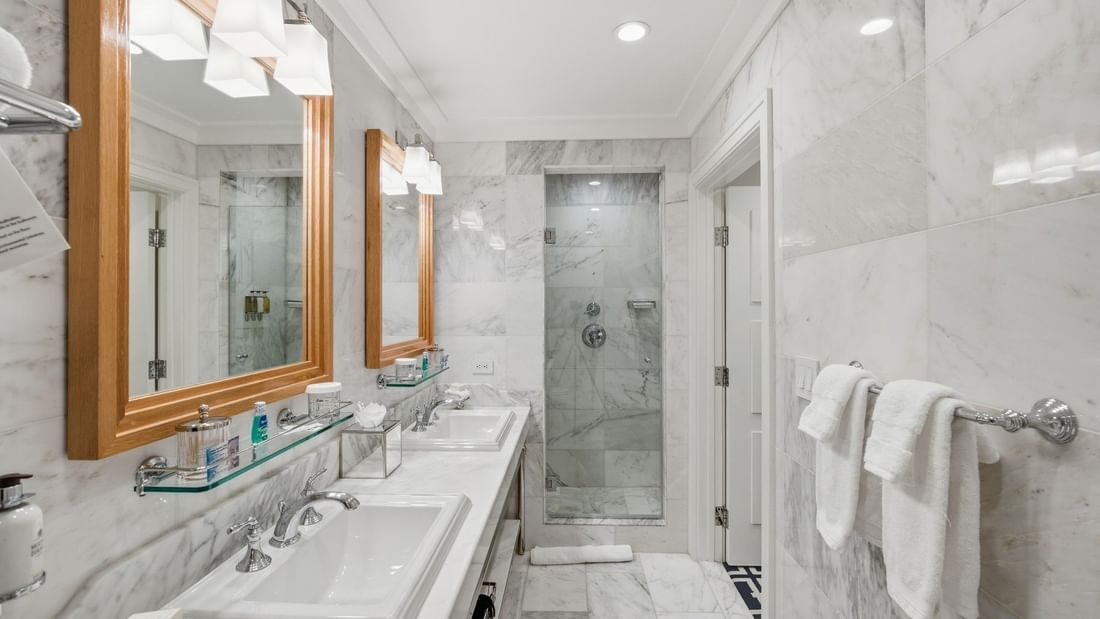 Grand Deluxe Suite bathroom with marble finishes, dual vanities, and glass-enclosed shower at el PRADO Hotel, Palo Alto