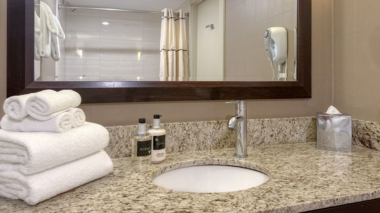 Bathroom with large mirror, sink, towels and soaps.
