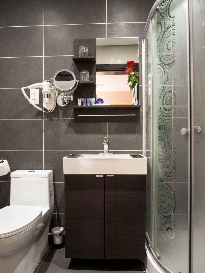 Standard room bathroom featuring a vanity with a lavatory by the glass shower at Naviti By Warwick Dammam