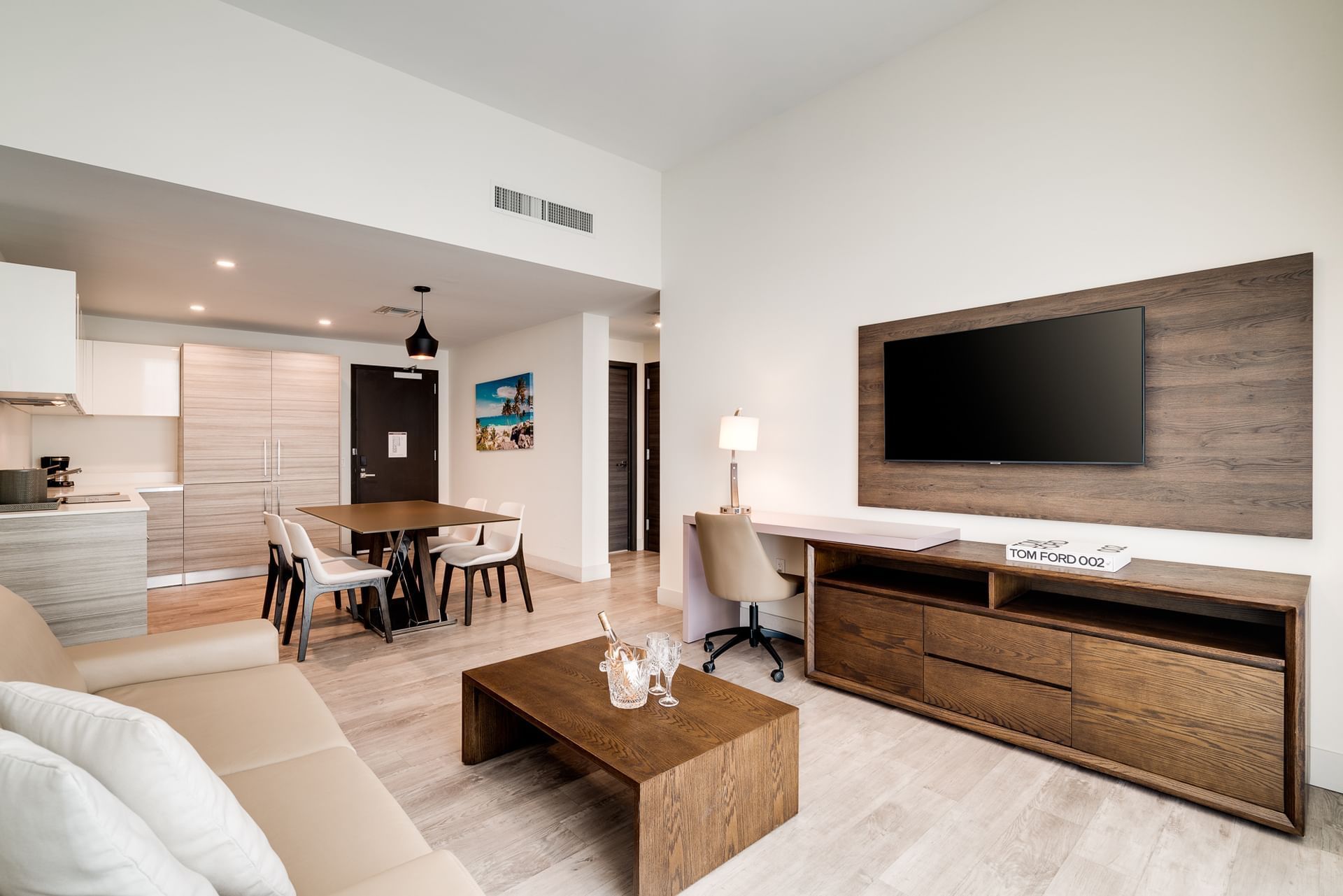 A modern living room with a kitchenette, dining area, and TV