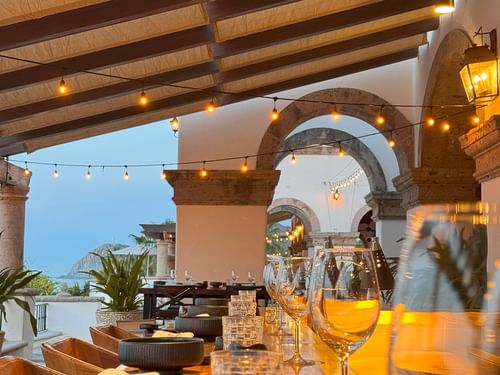 Comedor La Terraza del Santo con una mesa larga con cristalería y guirnaldas de luces en Hacienda del Mar Los Cabos