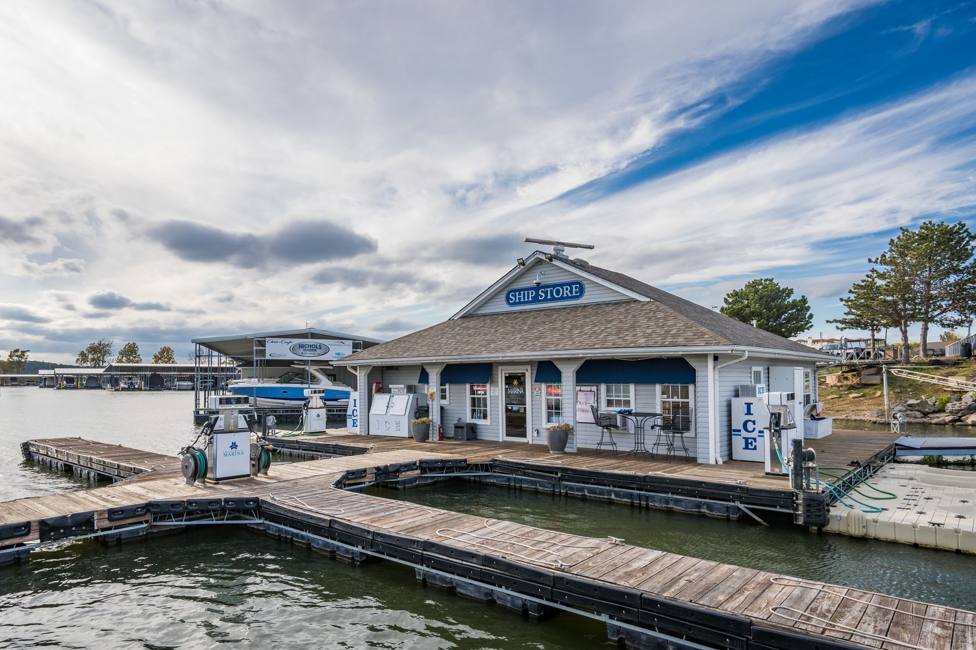 Wide-angle view of a floating marina, ship store & fuel docks under a cloudy blue sky at Shangri-La Resort and Golf Club