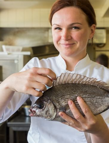 Chef holding a fresh fish in the kitchen, The Originals Hotels