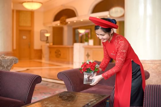 A girl putting a vase on table near sofas at Hanoi Daewoo Hotel