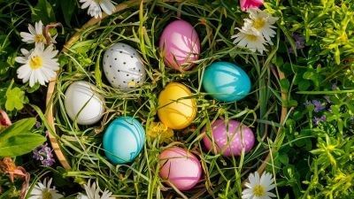 A basket of colorful Easter eggs surrounded by vibrant flowers and green grass, celebrating the joy of spring.
