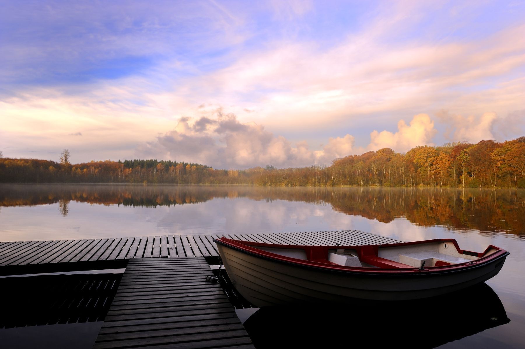 Row boat at dock with beautiful sunset over lake