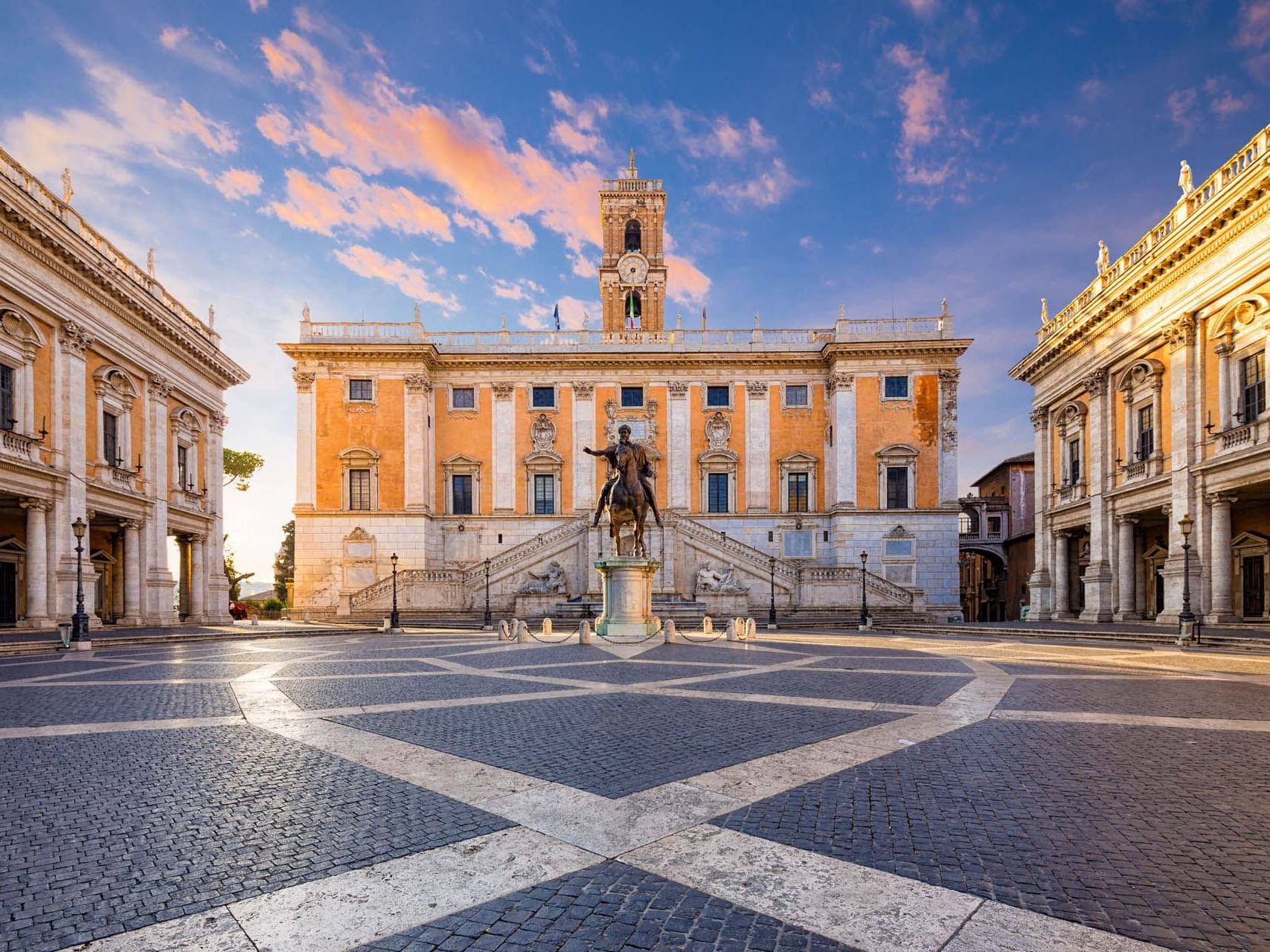 Piazza del Campidoglio with Marcus Aurelius' statue, historic buildings, and a sunset sky near The Guardian Hotel