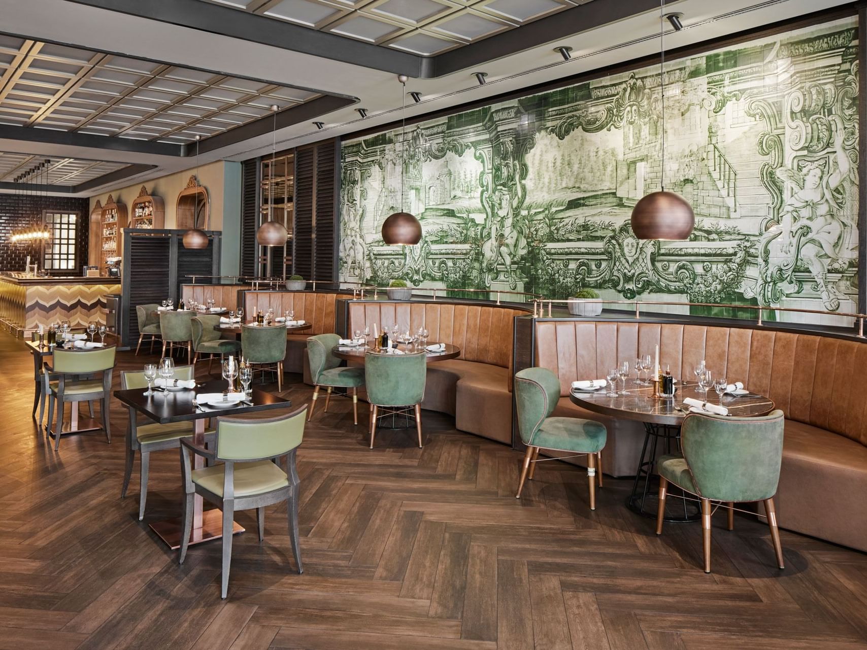 Elegantes Restaurant mit gemusterten Wänden, Holzboden und runden Tischen mit grünen Stühlen – Titanic Chaussee Berlin.