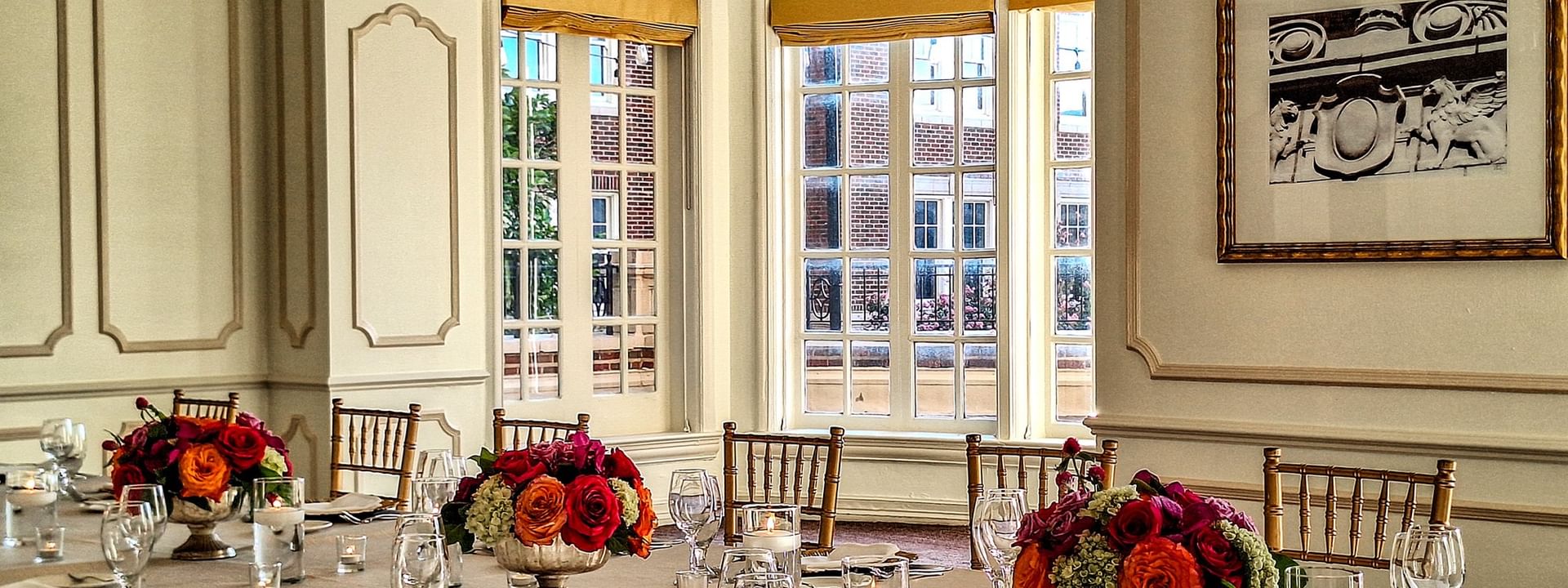 Dining table with flowers by gold chairs under a crystal chandelier in The Bridewell Suite at Warwick Melrose Dallas
