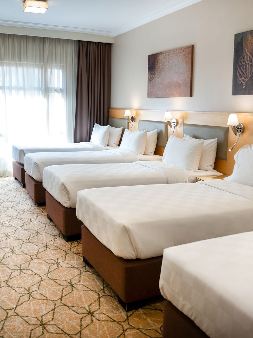 أربعة أسرّة مزودة بملاءات ووسائد بيضاء في غرفة فندقية في فندق سجى ورويك المدينة المنورة.