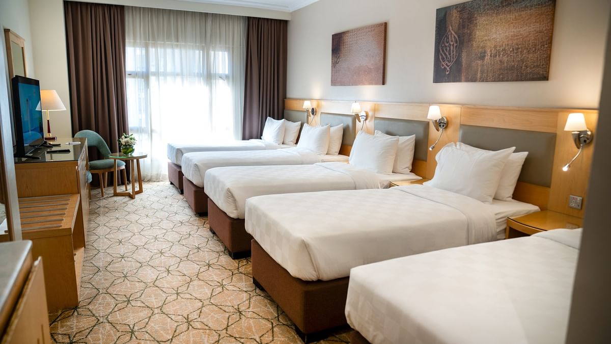 أربعة أسرّة مزودة بملاءات ووسائد بيضاء في غرفة فندقية في فندق سجى ورويك المدينة المنورة.