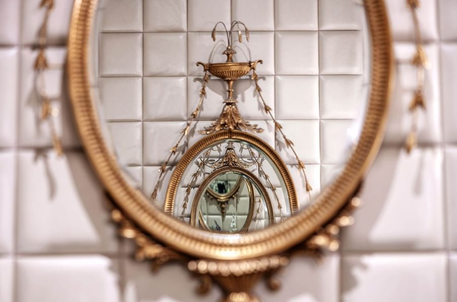 Gold ornate mirror with white tile background in hotel room at Warwick New York.