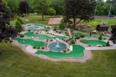 Aerial view of outdoor mini-golf course with a fountain, surrounded by trees by The Lodge at Schroon Lake