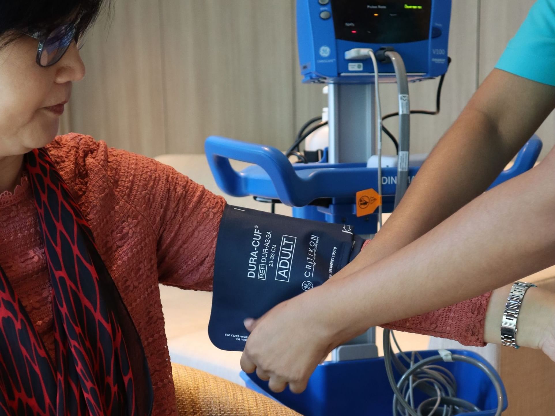 A nurse checking a woman's blood pressure with a cuff at MiCasa All Suite Hotel KL