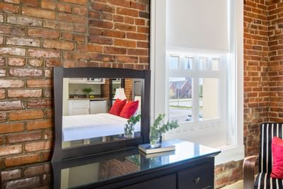 Dressing table with a mirror, brick wall & window in Queen Premiere Midtown at Retro Suites Hotel