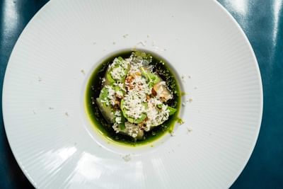 Gourmet dish with green sauce, fresh herbs, and crumbled cheese served in Ciaorigato Restaurant at Hotel Bijou