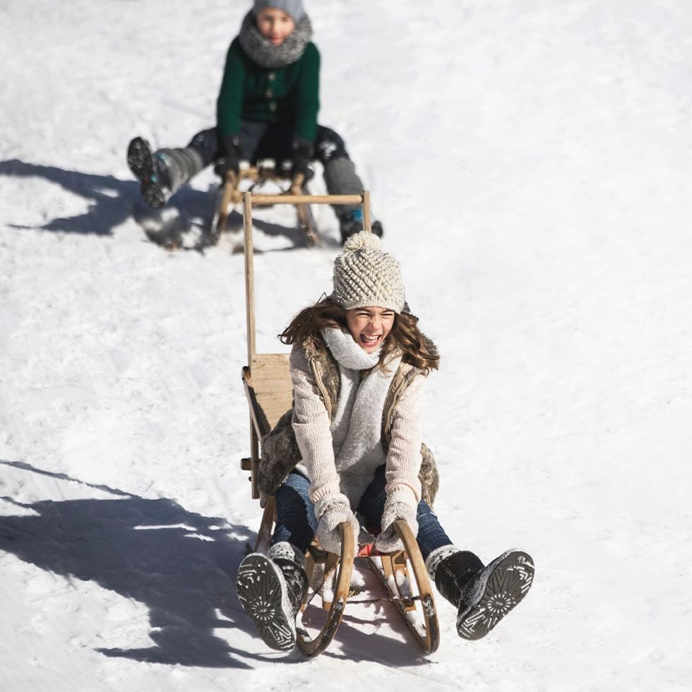 A kid enjoying a sleigh ride near Falkensteiner Hotels