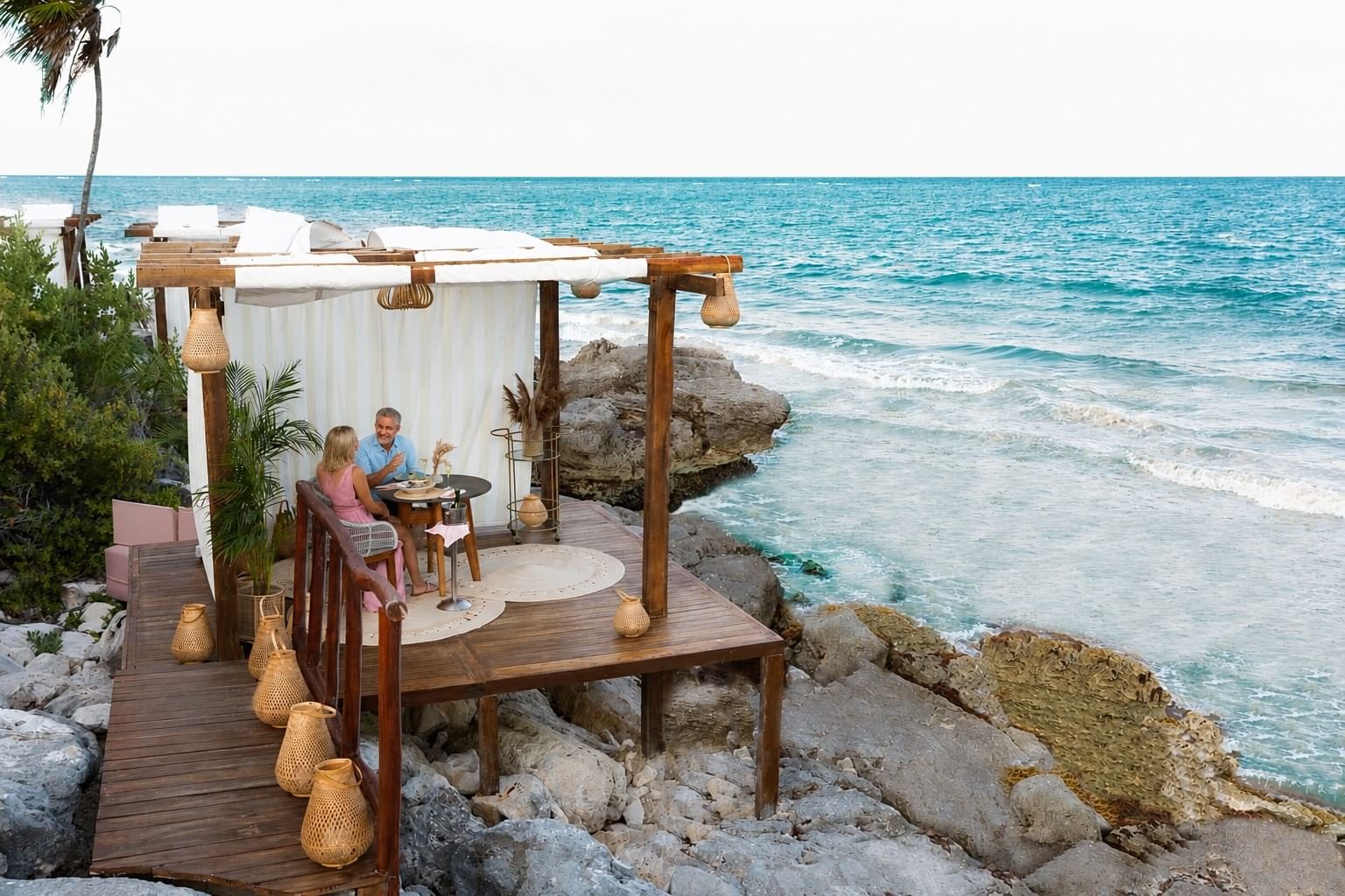 Couple dining in a private cabana above Mi Amor's rocky Caribbean coast