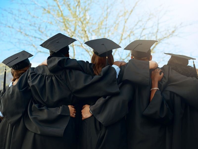 graduates in black gowns and tassels at a nearby university graduation to el PRADO Hotel