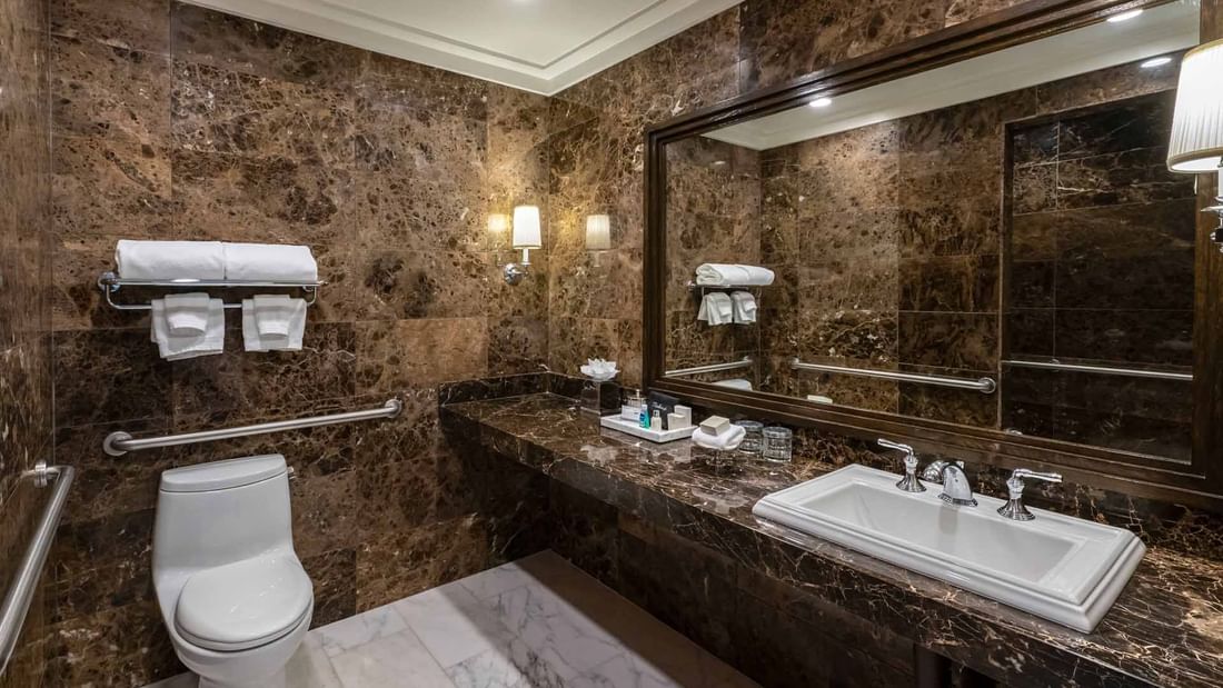 Bathroom with dark marble walls, grab bars, and a spacious vanity in Deluxe Queen Mobility and Hearing at El Prado Hotel