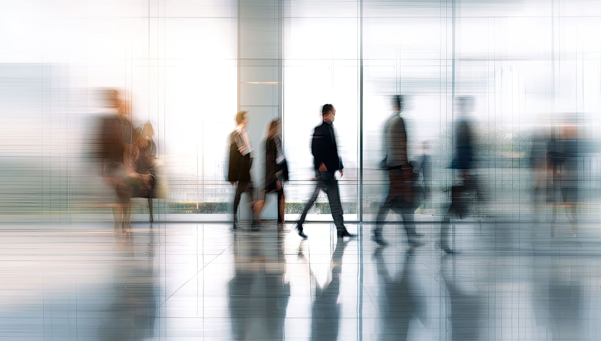 Motion blur of business professionals walking through a bright glass lobby area at Residhotel
