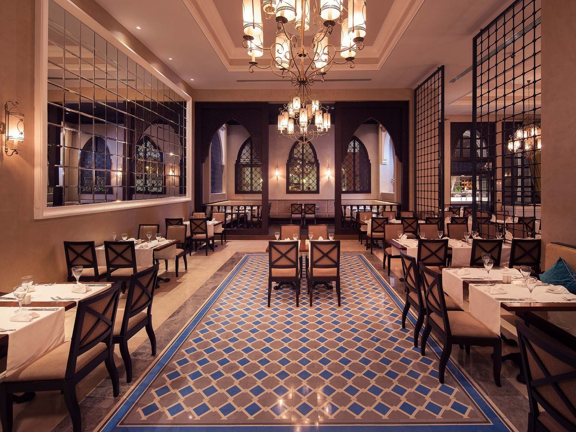 Elegant restaurant interior with ornate chandeliers, tiled floor, and set dining tables at Titanic Deluxe Golf Belek