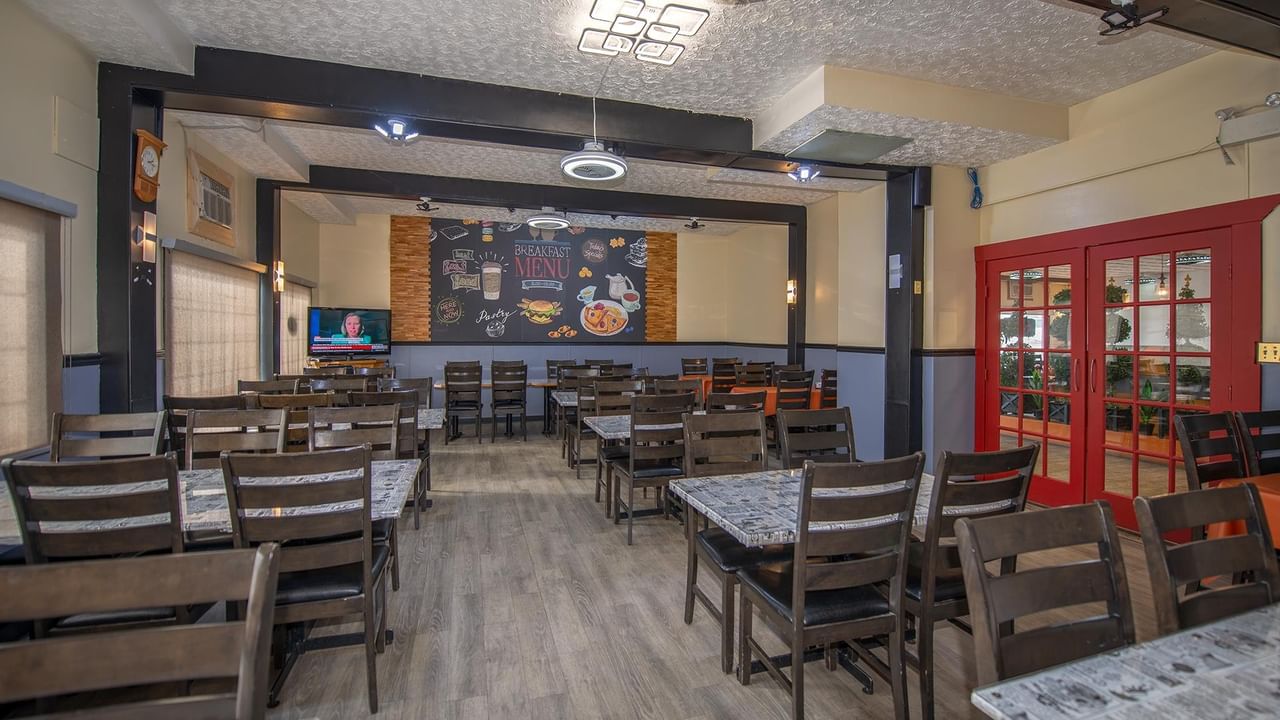Interior view of a dining area with tables, chairs, and a menu board.