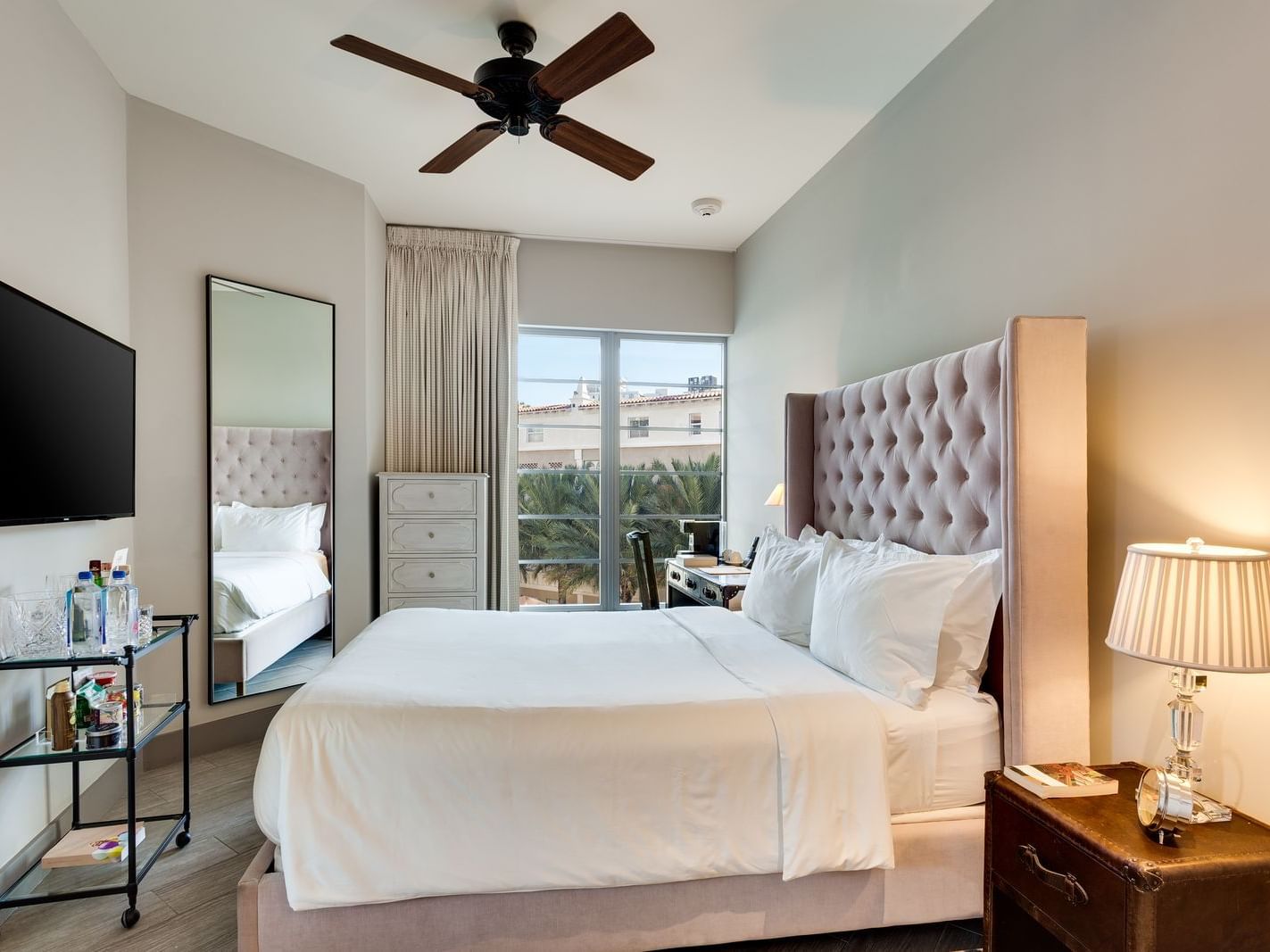 room with large bed, small bar and tall mirror