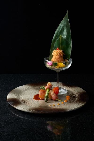 Elegant dish with floral garnish, glass and plated meat with asparagus and sauces at The Saujana Hotel Kuala Lumpur