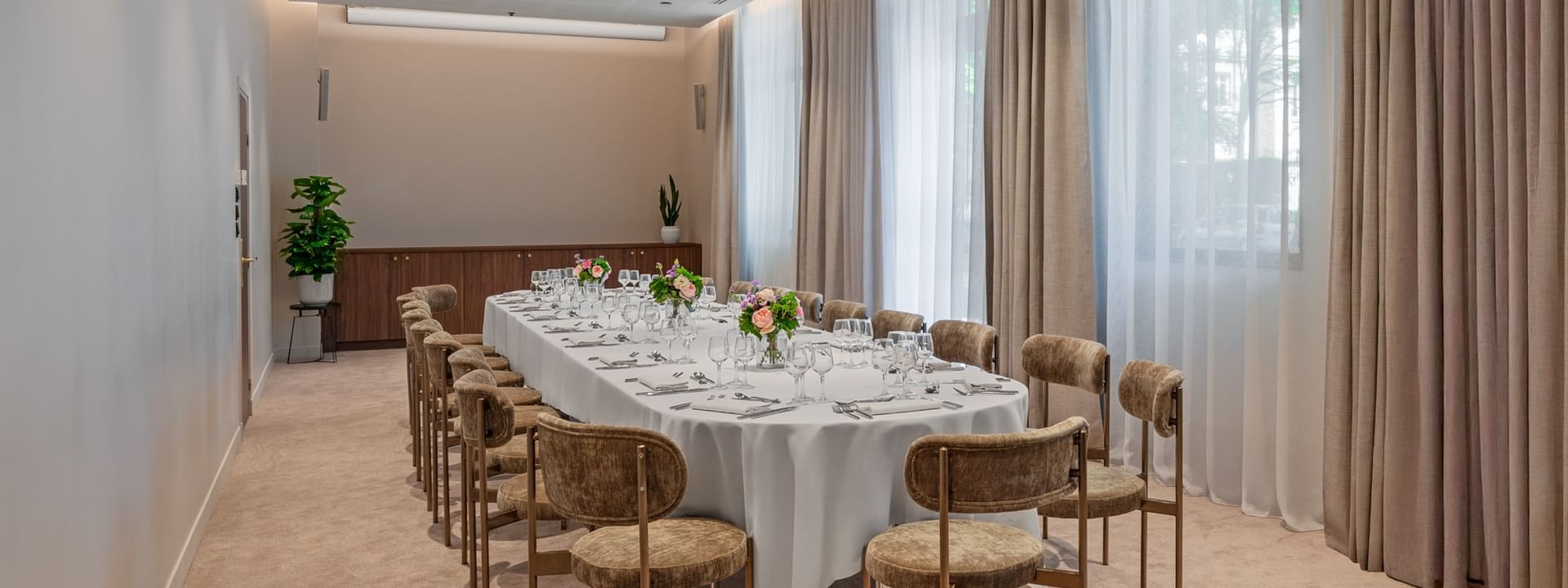 Long dining table with floral centerpieces and large windows in Windsor meeting room at Warwick Reine Astrid - Lyon