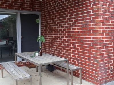 Outdoor seating with table and benches next to a red brick wall at La Trobe University Regional Housing - Ballarat.