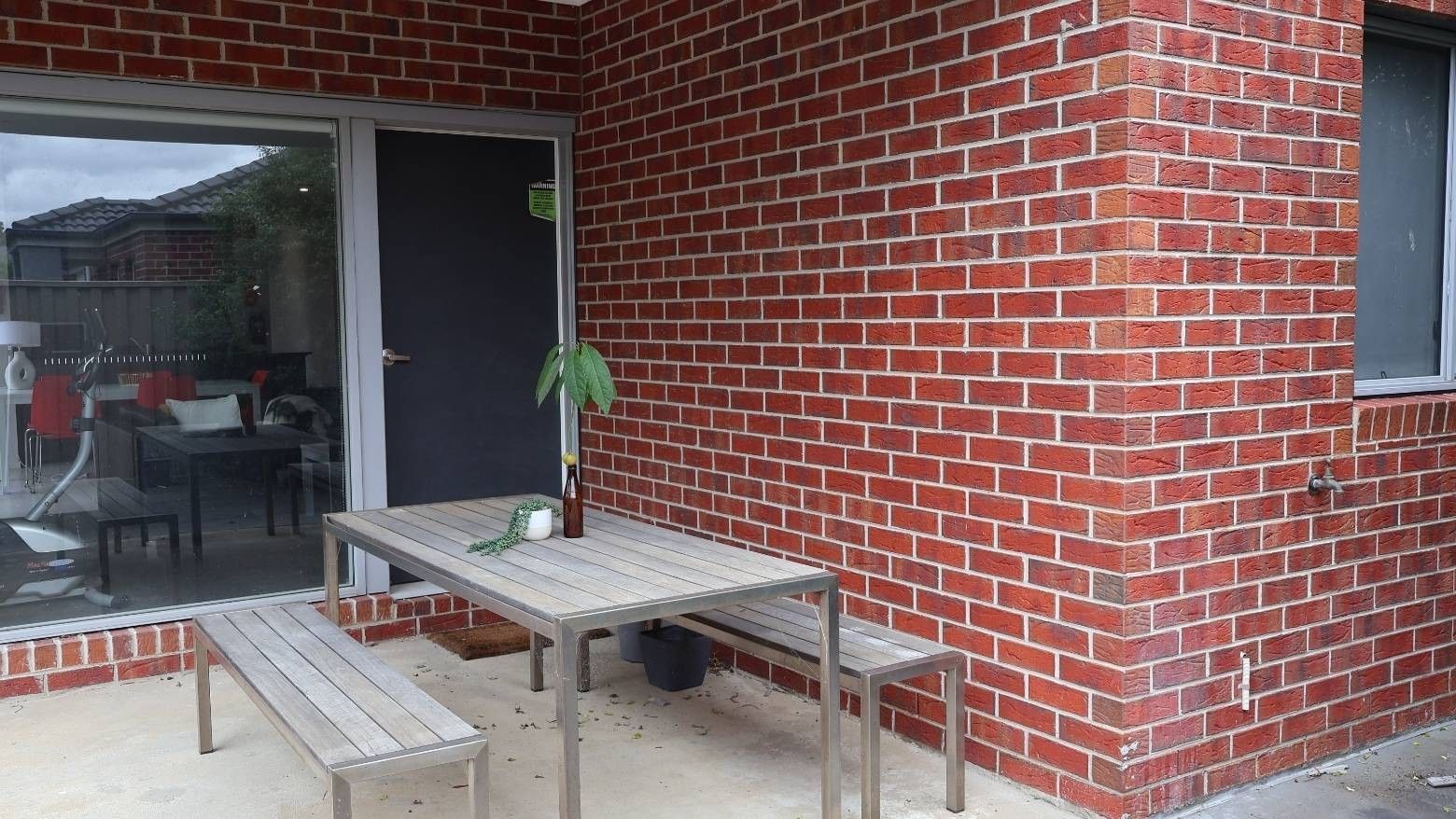 Outdoor seating with table and benches next to a red brick wall at La Trobe University Regional Housing - Ballarat.