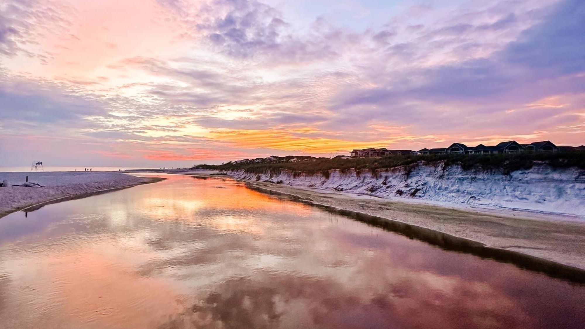 Sunset over a the Watersound Beach Club dune lake outfall reflecting the sky and the Watersound Beach community homes and condos in the background.