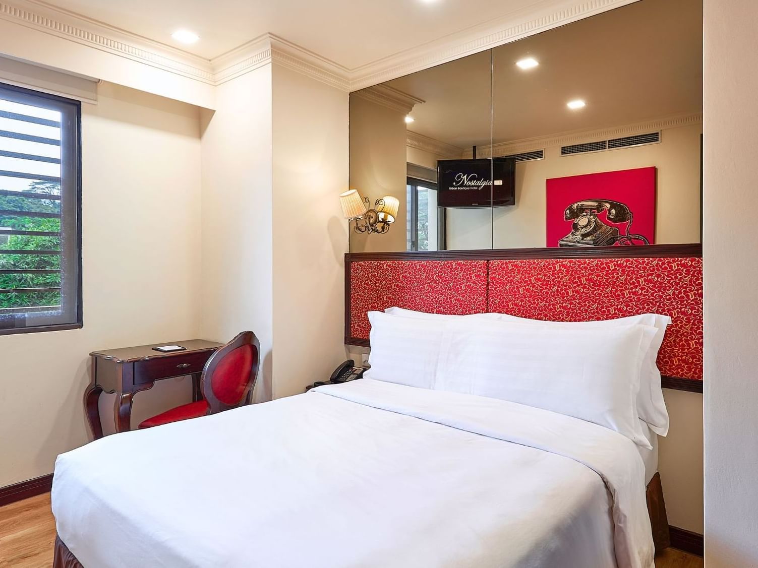 Large bed with comfy pillows & work desk in Deluxe Queen Room at Nostalgia Hotel Singapore